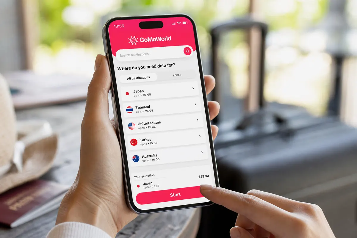 Close-up of a person's hands tapping the Start button in the GoMoWorld application on a smartphone